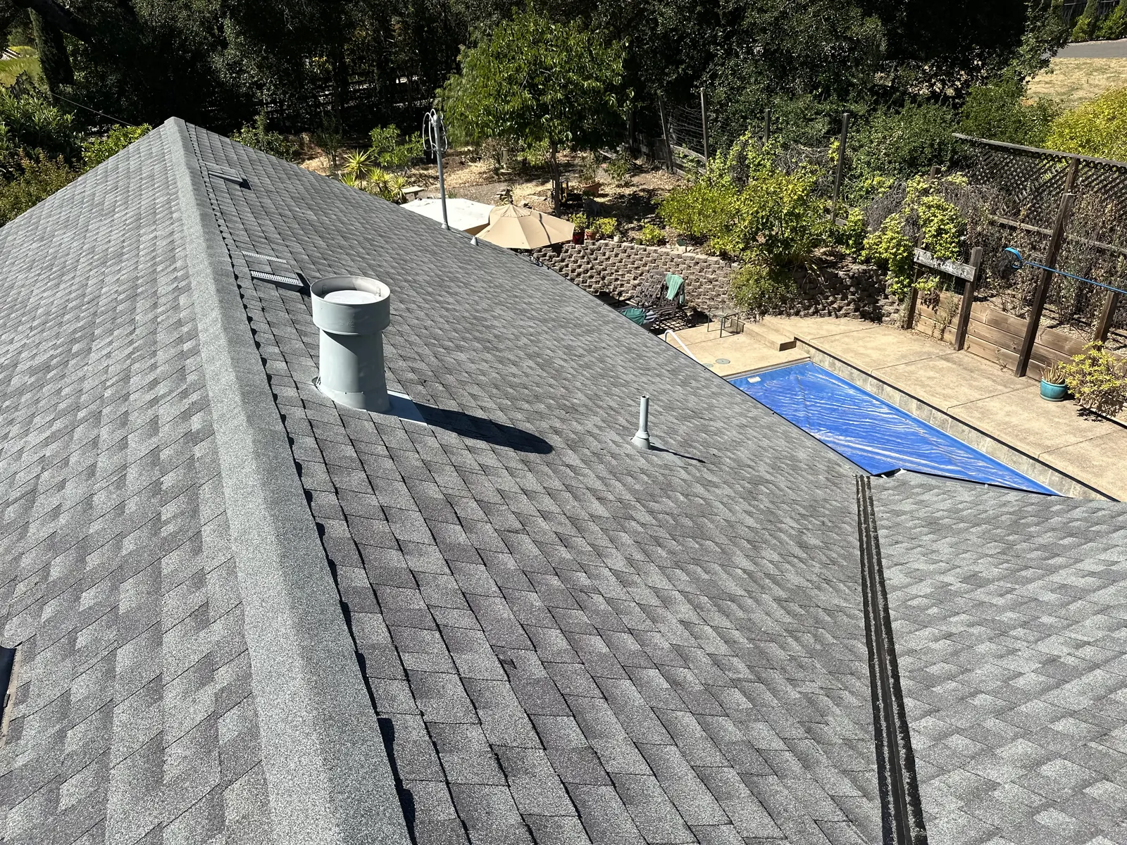 Completed charcoal architectural shingle roof with ridge line and pipe-vent flashing on a Sonoma home