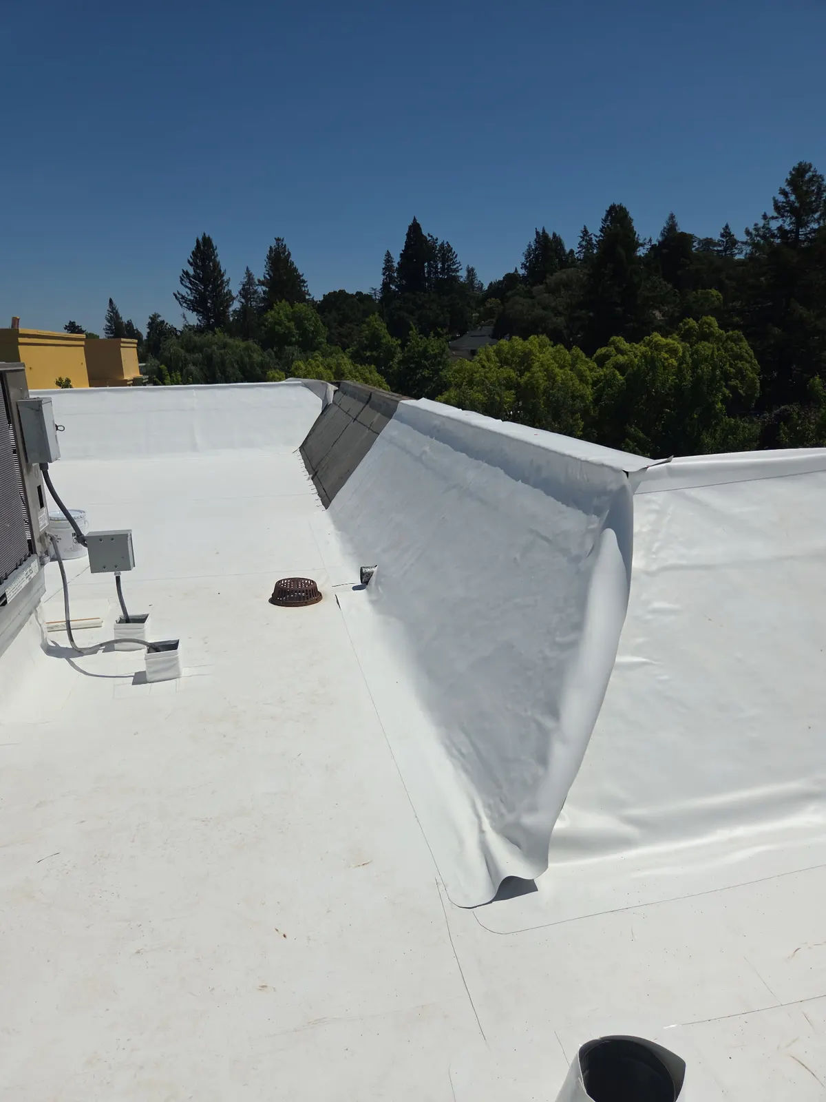 Commercial TPO flat roof with tapered crickets for positive drainage in Santa Rosa