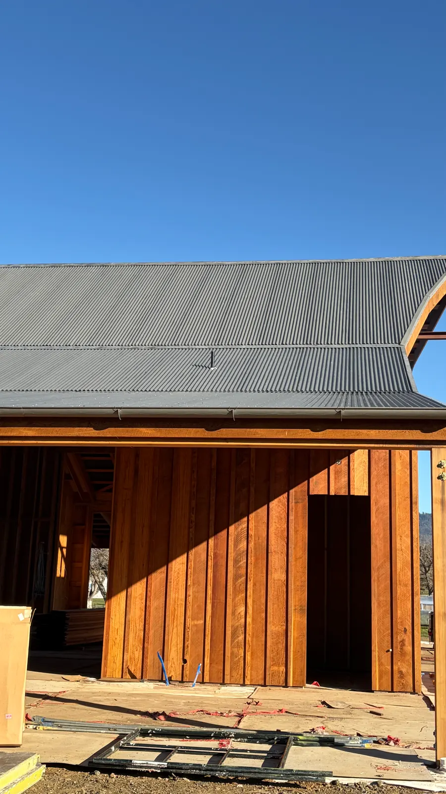 Curved standing-seam metal roof on a modern wood-sided barn build