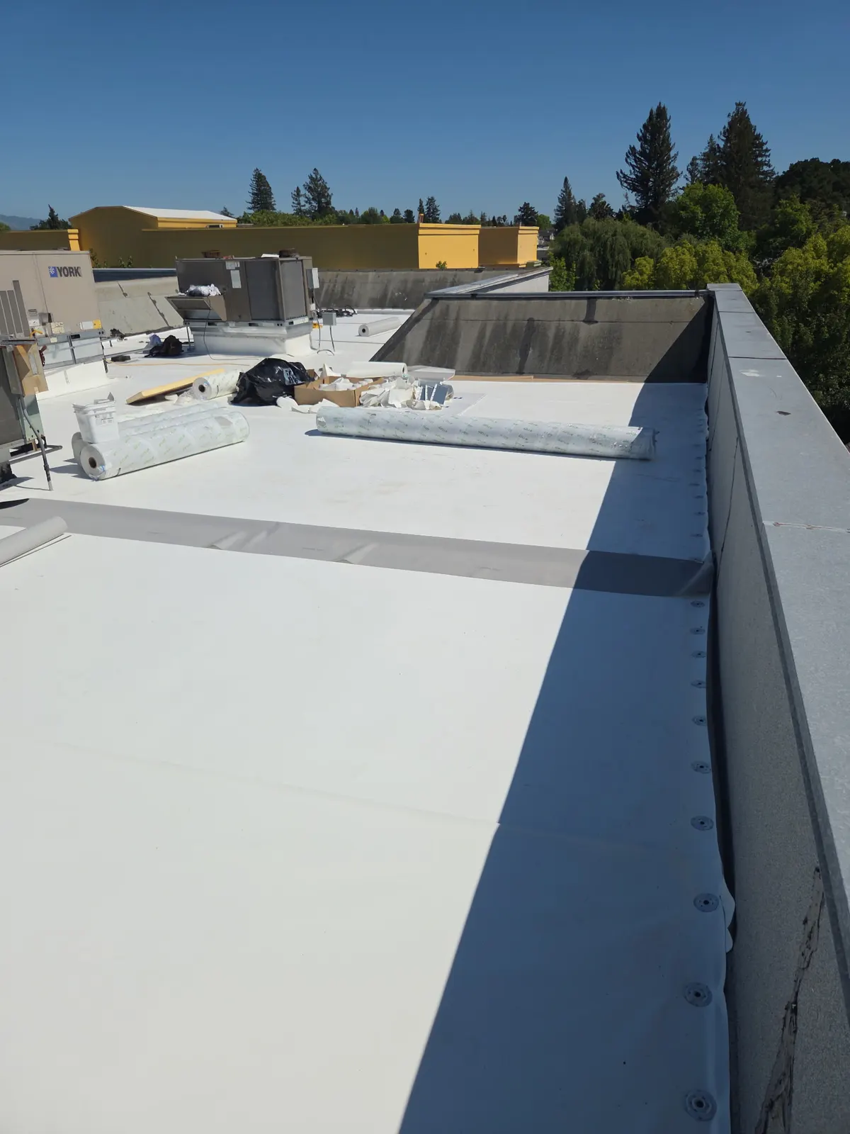 Low-slope roof insert with copper edge detail in a shingle roof beside a brick chimney
