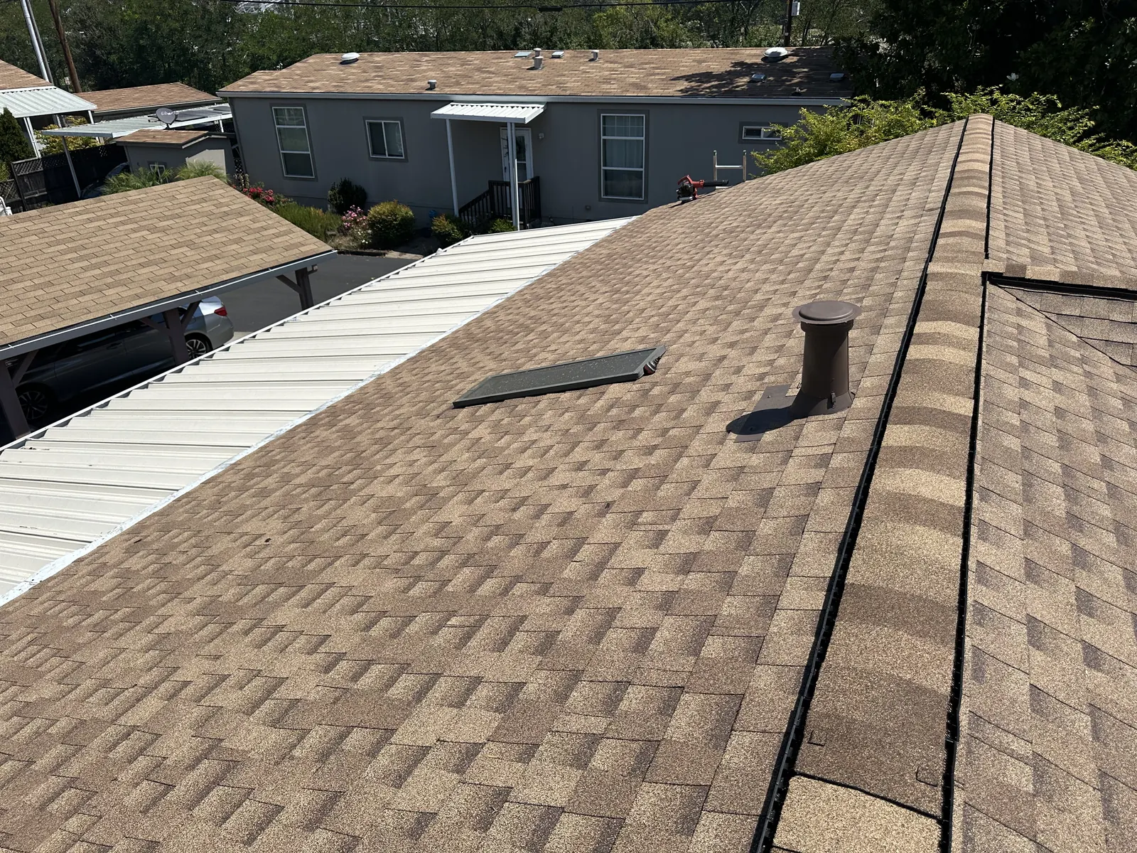 New shingle roof with vent boot beside a white metal awning roof on a Healdsburg manufactured home