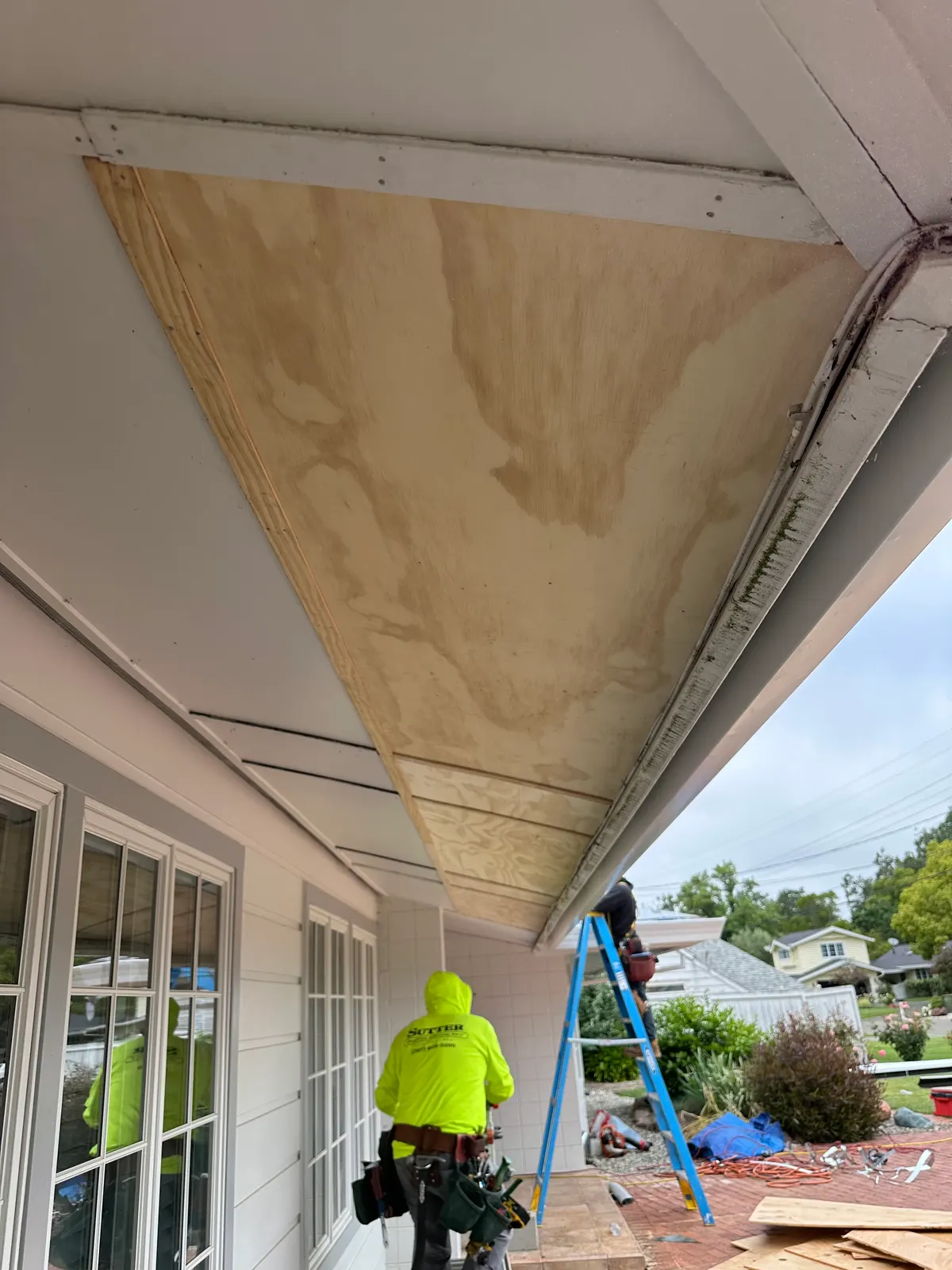 New plywood soffit installed over a porch with crew member below