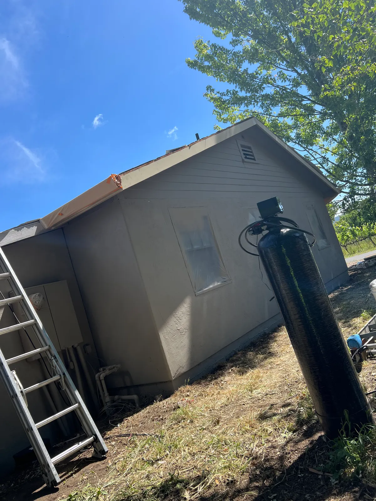 Re-roof in progress with ladder staged against a stucco home