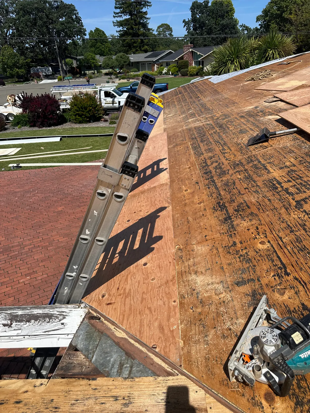Roof tear-off in progress with ladders staged on the exposed deck
