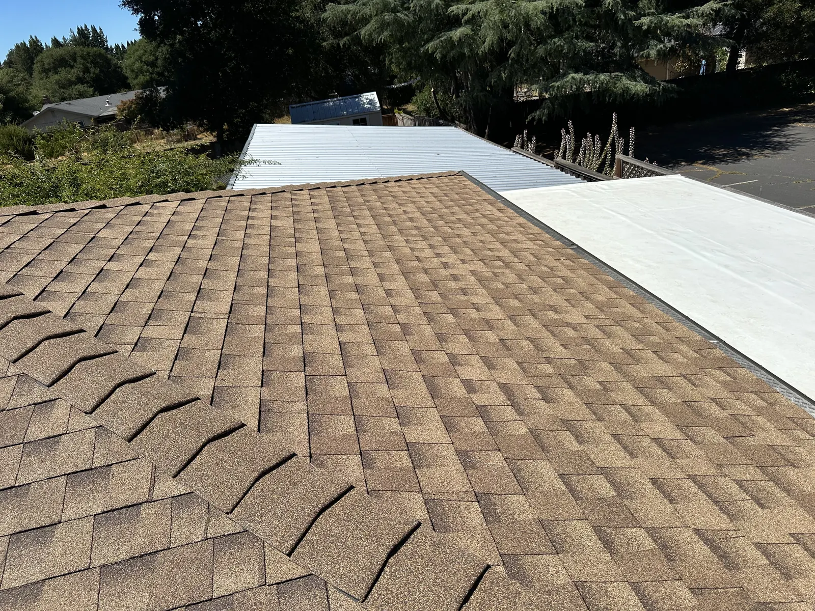 New tan architectural shingle roof meeting a white metal awning roof on a Sebastopol home