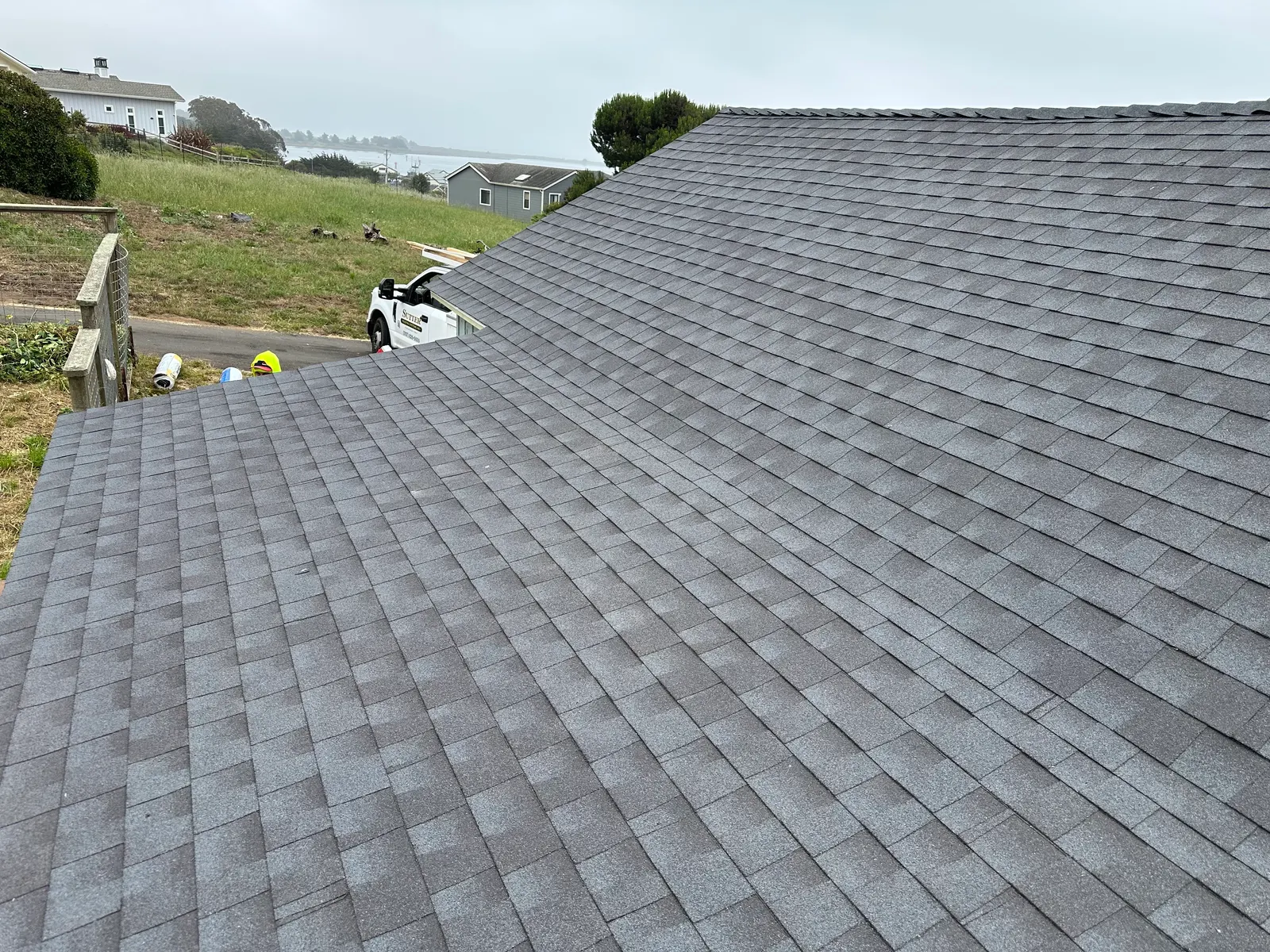 Completed shingle roof replacement with coastal fog rolling in
