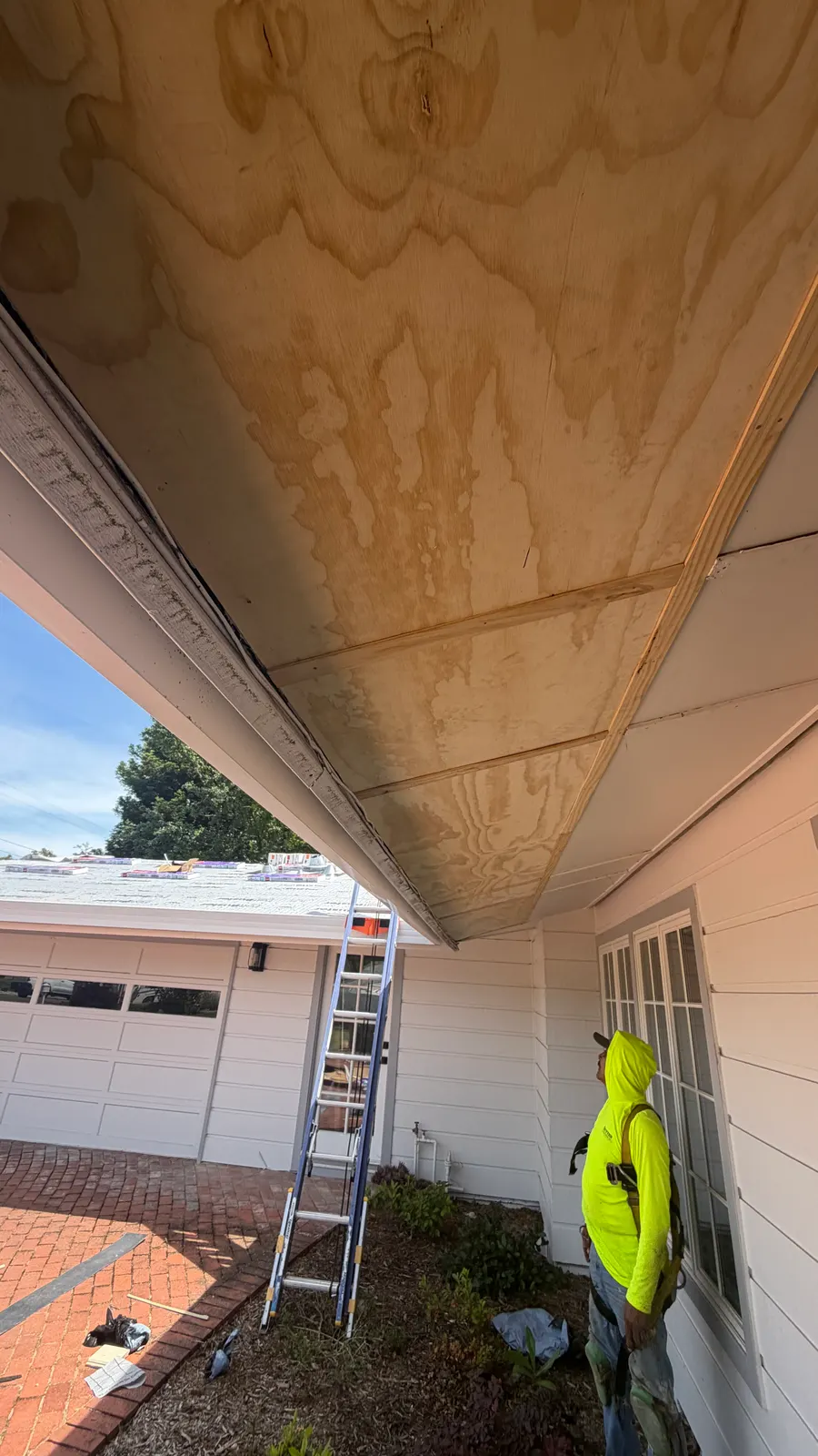Soffit repair underside view with crew member at the ladder